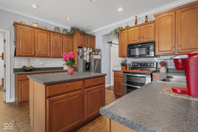 kitchen with appliances with stainless steel finishes, decorative backsplash, a barn door, and a kitchen island