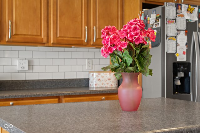 room details featuring tasteful backsplash and stainless steel refrigerator with ice dispenser