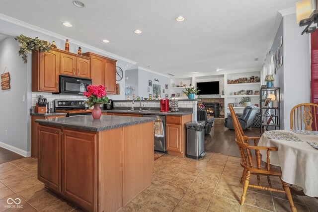 kitchen featuring stainless steel appliances, built in features, ornamental molding, and a kitchen island