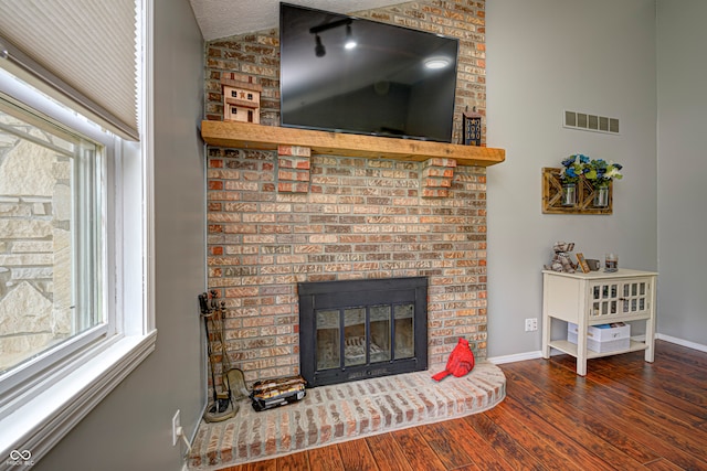 living room with dark wood-type flooring, vaulted ceiling, a fireplace, and a textured ceiling