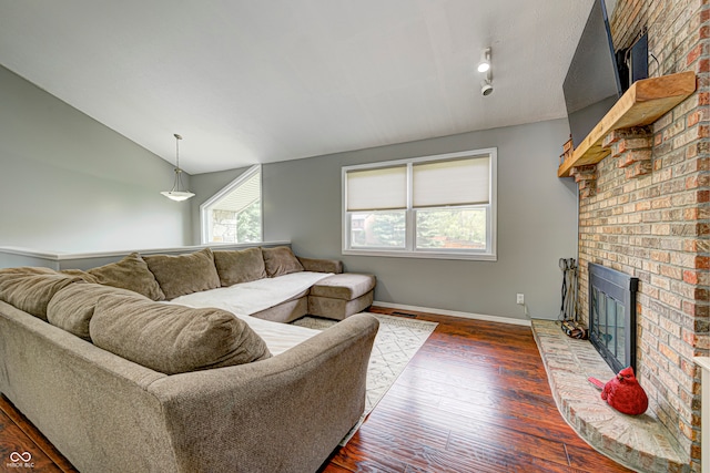 living room featuring a brick fireplace, dark wood-type flooring, and vaulted ceiling