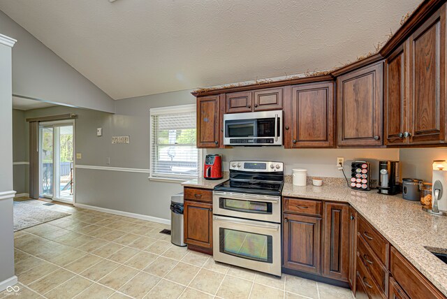 kitchen featuring light tile patterned floors, stainless steel appliances, lofted ceiling, and plenty of natural light