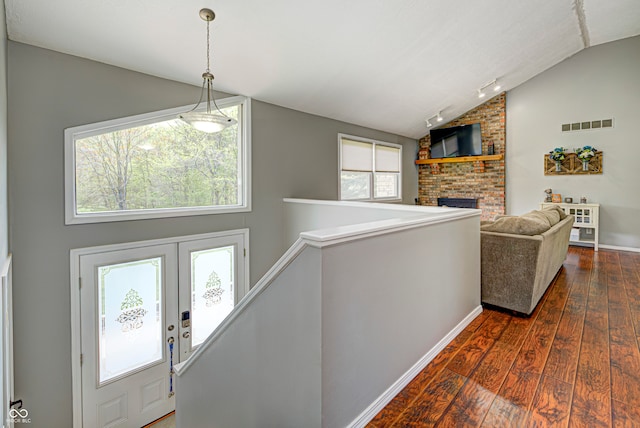 entrance foyer featuring lofted ceiling, a healthy amount of sunlight, dark wood-type flooring, and a brick fireplace