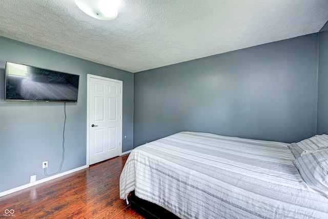 bedroom featuring a textured ceiling and dark hardwood / wood-style flooring