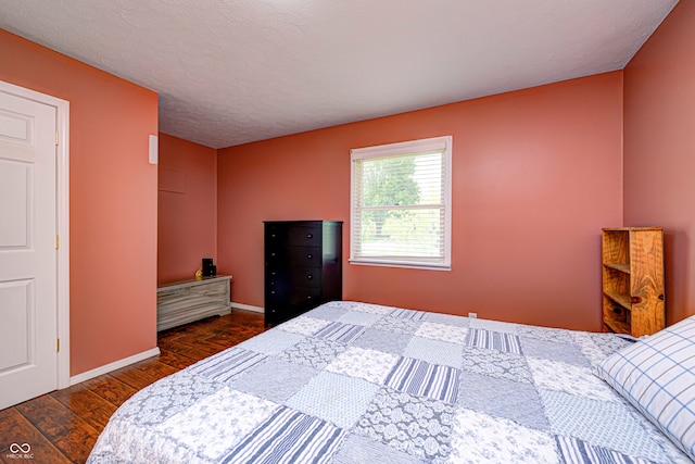 bedroom with a textured ceiling and dark hardwood / wood-style floors