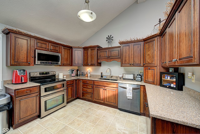 kitchen featuring appliances with stainless steel finishes, sink, light stone counters, and vaulted ceiling