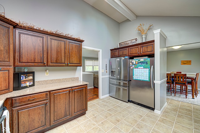 kitchen featuring light tile patterned flooring, stainless steel fridge with ice dispenser, vaulted ceiling with beams, and stainless steel fridge