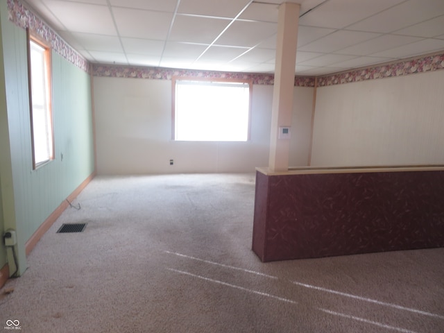 unfurnished room featuring a paneled ceiling, a healthy amount of sunlight, and carpet flooring