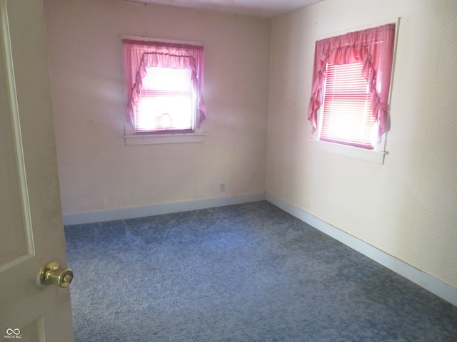 empty room featuring dark carpet and a wealth of natural light