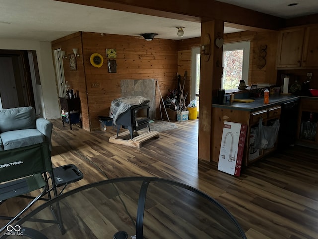 interior space featuring dark wood-type flooring, wood walls, a wood stove, and dishwasher