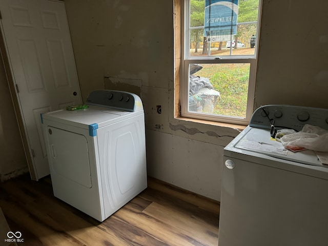 clothes washing area with light wood-type flooring, washing machine and dryer, and plenty of natural light