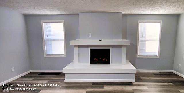 12544 S State Road 3, Westport, IN 47283 - unfurnished living room featuring a textured ceiling, a fireplace with raised hearth, dark wood finished floors, and baseboards