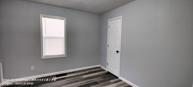 empty room featuring dark hardwood / wood-style floors, a textured ceiling, and a wealth of natural light