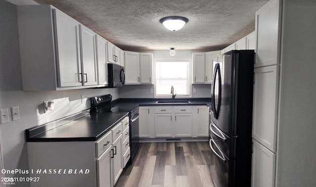 kitchen with black appliances, sink, dark hardwood / wood-style floors, and white cabinets