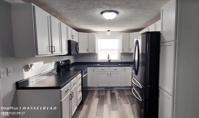 12544 S State Road 3, Westport, IN 47283 - kitchen featuring a sink, black appliances, dark countertops, a textured ceiling, and dark wood-style floors
