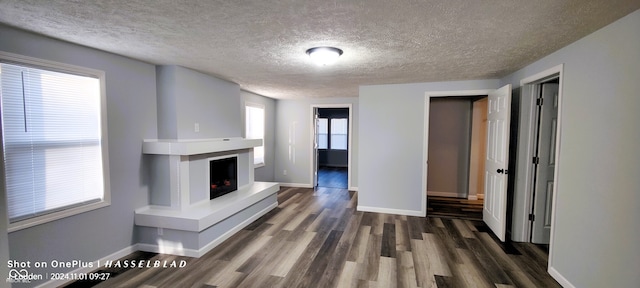 unfurnished living room with a textured ceiling and dark hardwood / wood-style flooring