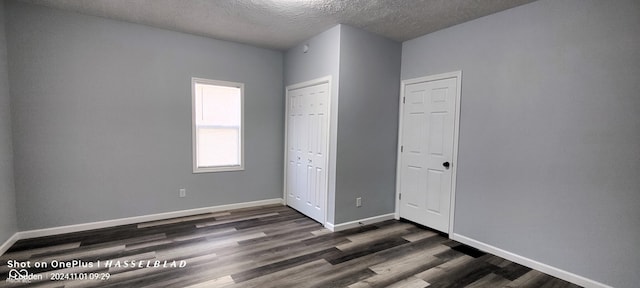 unfurnished bedroom featuring a textured ceiling and dark hardwood / wood-style floors