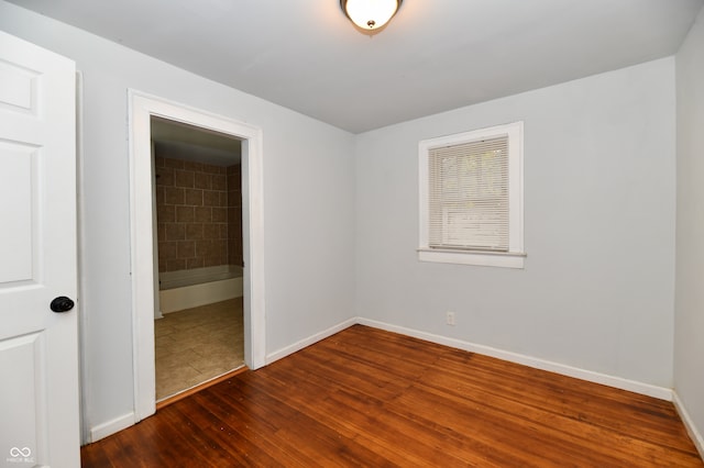 unfurnished bedroom featuring connected bathroom, a closet, and dark hardwood / wood-style flooring