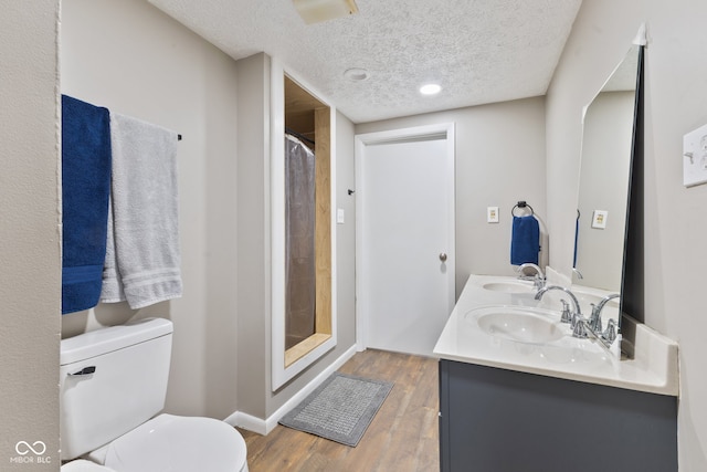 bathroom featuring toilet, walk in shower, vanity, and wood-type flooring