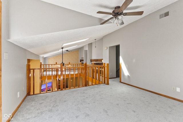 carpeted empty room featuring vaulted ceiling with skylight, a textured ceiling, and ceiling fan