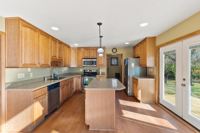 kitchen with a kitchen island, appliances with stainless steel finishes, light hardwood / wood-style flooring, pendant lighting, and sink