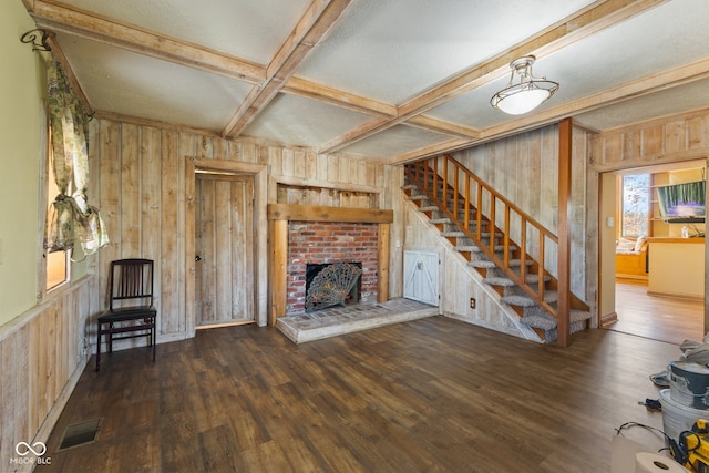 unfurnished living room featuring wood walls, a fireplace, coffered ceiling, beamed ceiling, and dark wood-type flooring