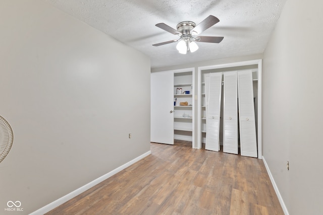 unfurnished bedroom featuring a textured ceiling, wood-type flooring, and ceiling fan