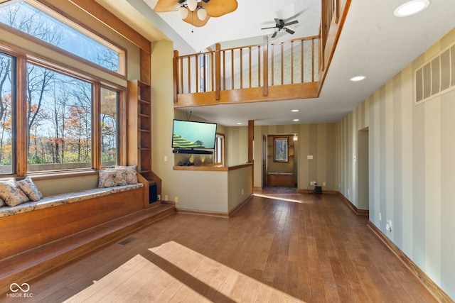 entrance foyer with a wealth of natural light, hardwood / wood-style floors, a towering ceiling, and ceiling fan