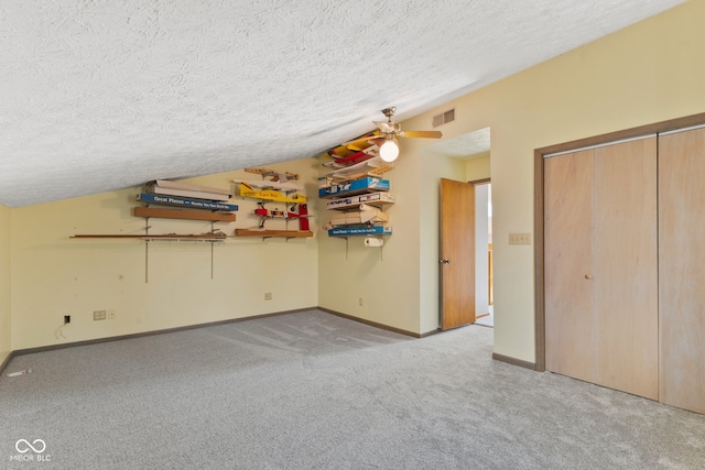 unfurnished bedroom with lofted ceiling, a textured ceiling, light colored carpet, and ceiling fan