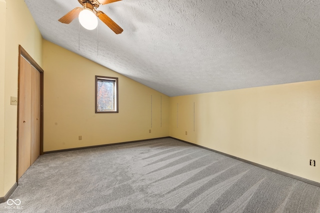 additional living space featuring lofted ceiling, a textured ceiling, light colored carpet, and ceiling fan