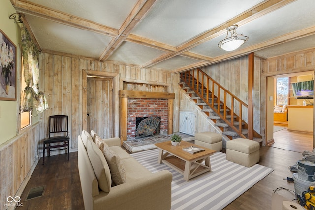 living room with wood walls, beam ceiling, a brick fireplace, and dark hardwood / wood-style flooring