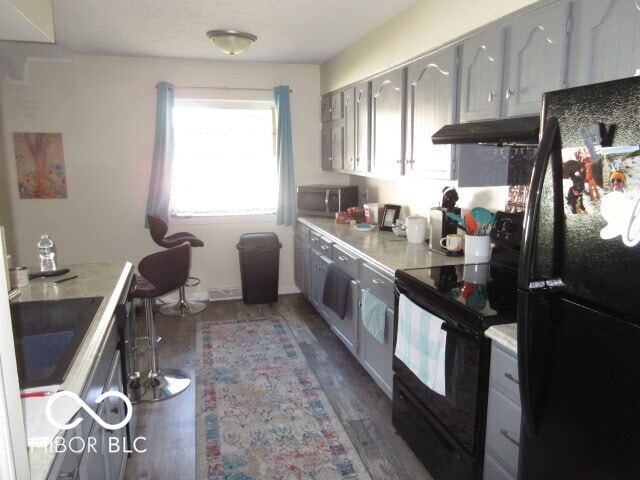 kitchen with gray cabinets, hardwood / wood-style flooring, and black appliances