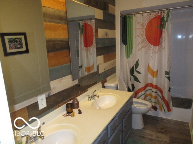 full bathroom featuring toilet, hardwood / wood-style floors, shower / bath combo with shower curtain, and vanity