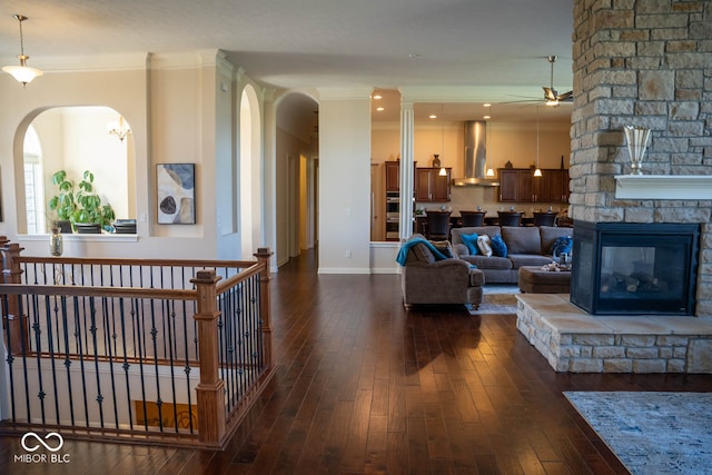 living room featuring a fireplace, ceiling fan, crown molding, and dark hardwood / wood-style flooring