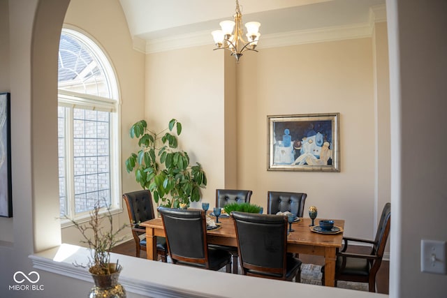 dining area featuring a chandelier, lofted ceiling, and ornamental molding