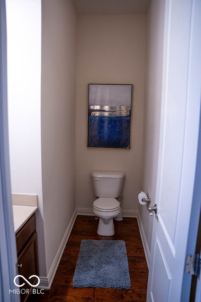 bathroom with toilet, vanity, and wood-type flooring