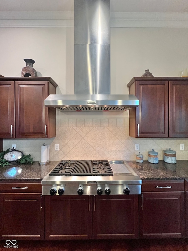 kitchen with dark stone counters, wall chimney range hood, stainless steel gas stovetop, and tasteful backsplash