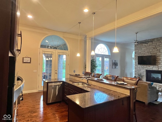 kitchen featuring a stone fireplace, french doors, hanging light fixtures, sink, and stainless steel dishwasher