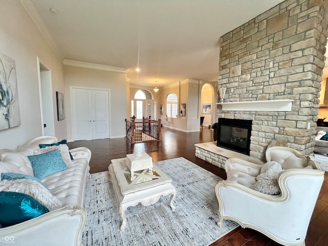 living room featuring a stone fireplace, dark hardwood / wood-style floors, and crown molding