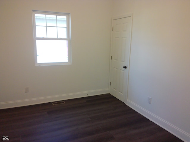 spare room with dark wood-type flooring and a healthy amount of sunlight