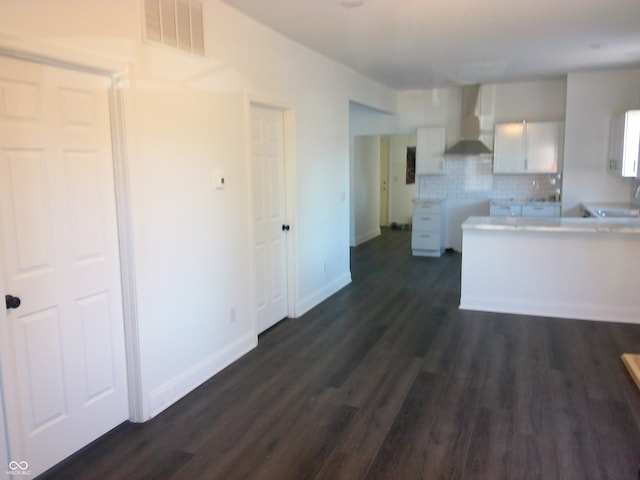 kitchen featuring white cabinets, wall chimney exhaust hood, dark hardwood / wood-style flooring, and tasteful backsplash