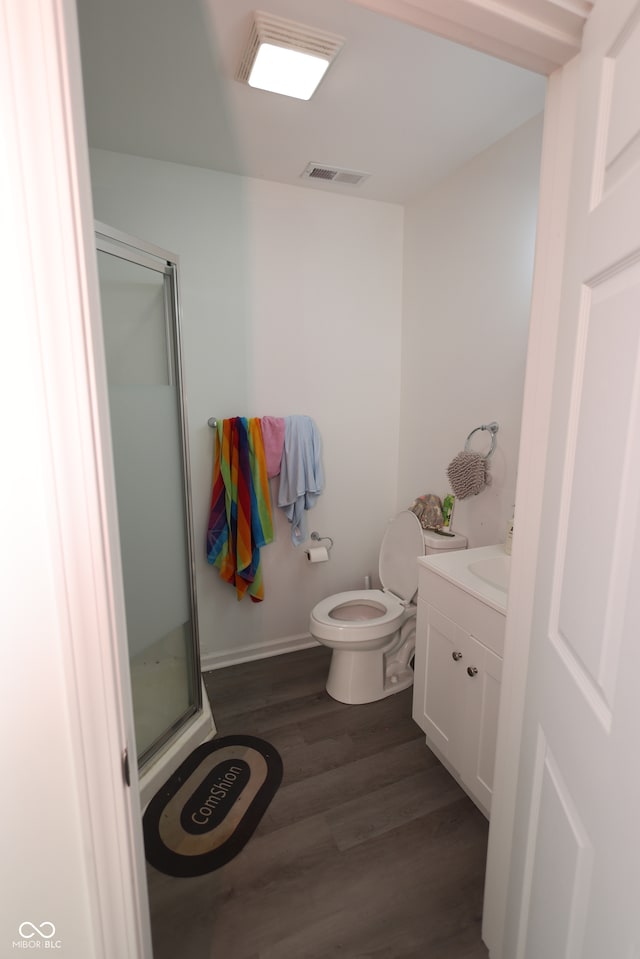 bathroom featuring toilet, vanity, wood-type flooring, and a shower with shower door