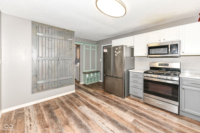 kitchen featuring appliances with stainless steel finishes, gray cabinetry, a textured ceiling, dark hardwood / wood-style floors, and white cabinetry