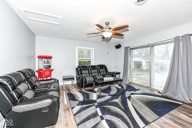 living room with ceiling fan, wood-type flooring, and a textured ceiling