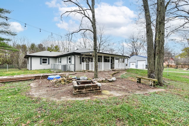 back of house with a yard and an outdoor fire pit