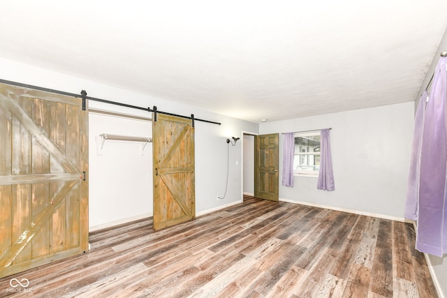 unfurnished bedroom featuring a barn door and wood-type flooring