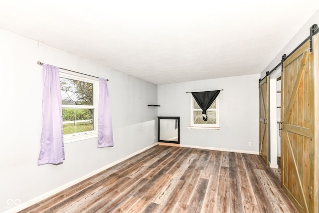 spare room featuring a barn door and dark wood-type flooring