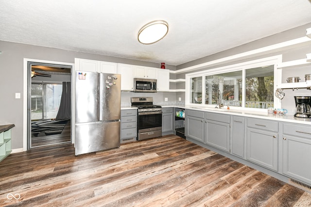 kitchen featuring stainless steel appliances, dark hardwood / wood-style flooring, a textured ceiling, gray cabinets, and white cabinets