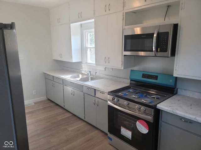 325 E Church St, Paragon, IN 46166 - kitchen featuring stainless steel appliances, a sink, light countertops, light wood-type flooring, and gray cabinetry