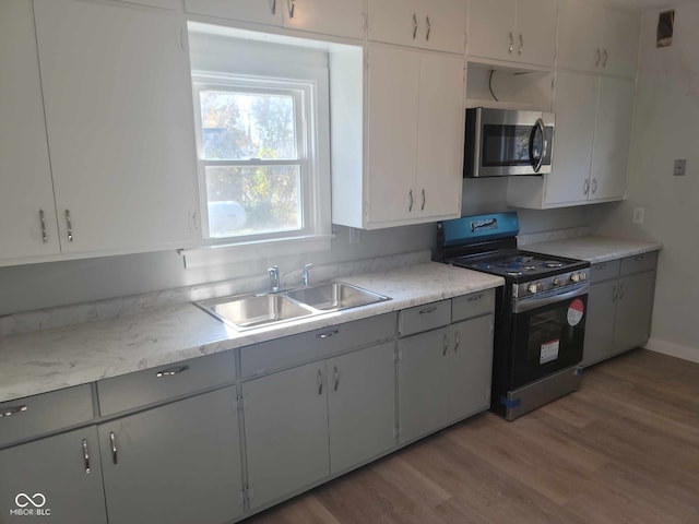 325 E Church St, Paragon, IN 46166 - kitchen featuring stainless steel microwave, black range with gas stovetop, a sink, light wood finished floors, and light countertops